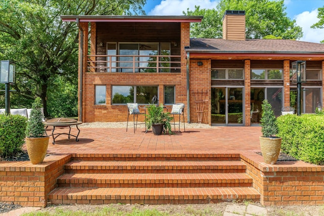 back of house with a balcony, an outdoor fire pit, and a patio area