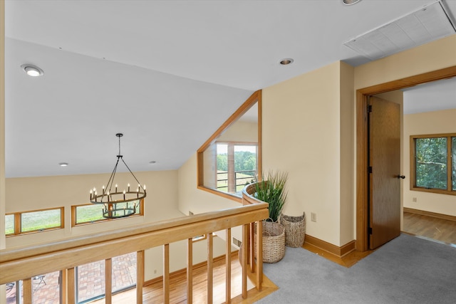 hallway featuring carpet, an inviting chandelier, and lofted ceiling