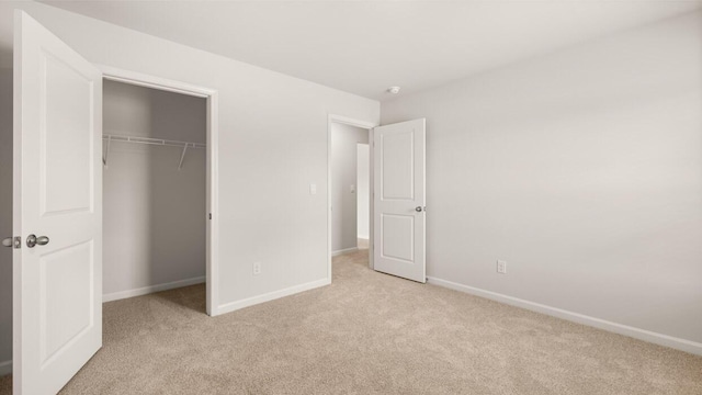 unfurnished bedroom with a closet and light colored carpet