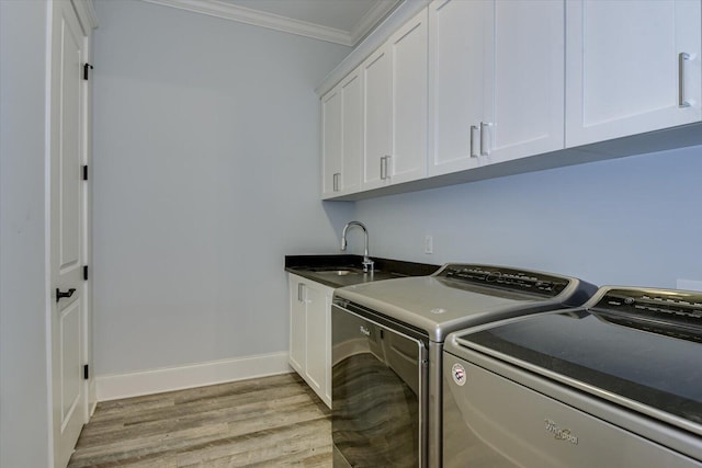 clothes washing area featuring sink, cabinets, separate washer and dryer, light hardwood / wood-style flooring, and crown molding