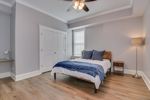 bedroom featuring ceiling fan, a closet, crown molding, and light hardwood / wood-style flooring