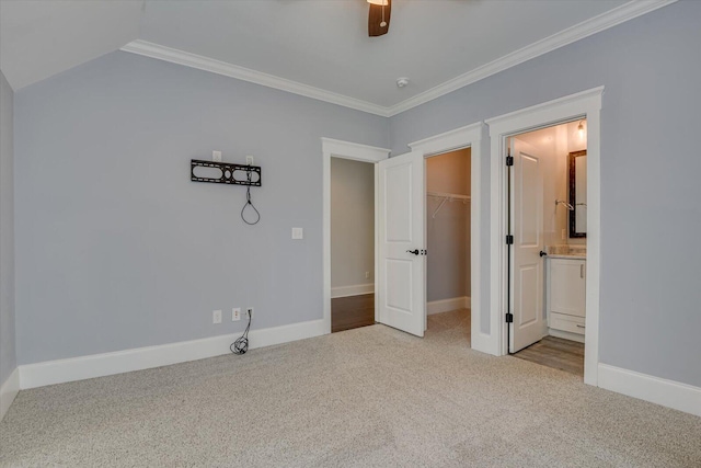 unfurnished bedroom featuring light colored carpet, ceiling fan, a spacious closet, connected bathroom, and a closet