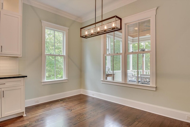 unfurnished dining area with dark hardwood / wood-style floors and ornamental molding