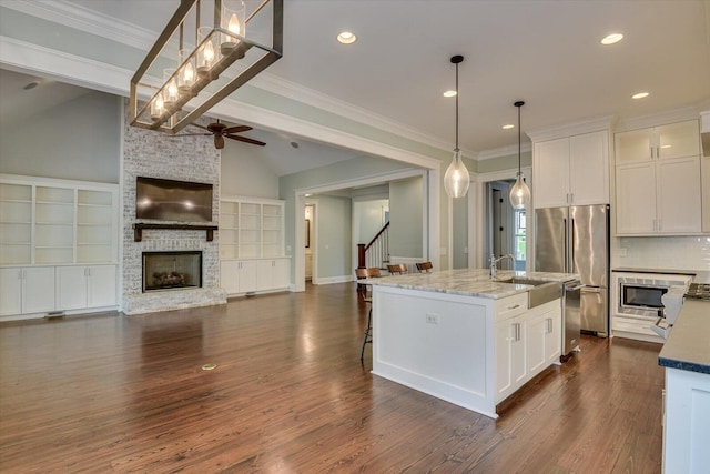 kitchen featuring white cabinetry, tasteful backsplash, a kitchen island with sink, and a fireplace