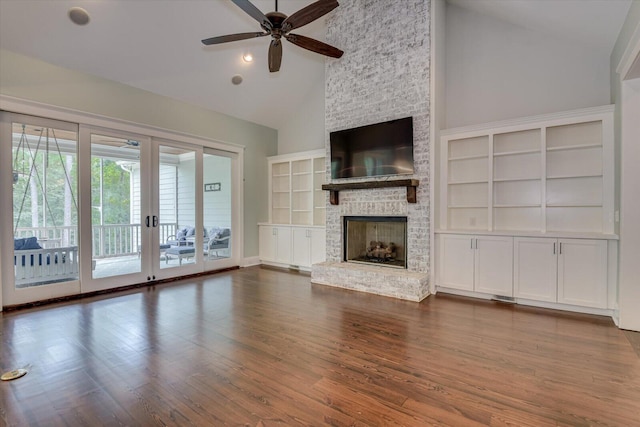 unfurnished living room featuring ceiling fan, french doors, dark wood-type flooring, a stone fireplace, and high vaulted ceiling