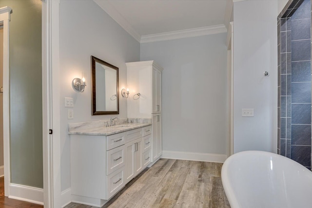 bathroom with vanity, wood-type flooring, ornamental molding, and a bath