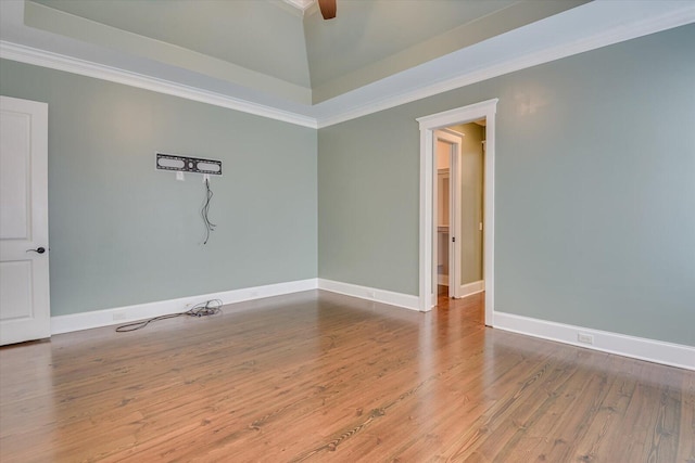 unfurnished room featuring a raised ceiling, crown molding, and wood-type flooring