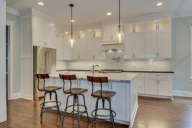 kitchen featuring white cabinetry, light stone countertops, tasteful backsplash, crown molding, and a kitchen island with sink