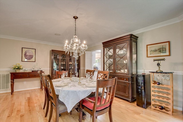 dining area with an inviting chandelier, light hardwood / wood-style floors, and ornamental molding