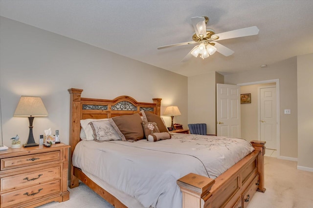 bedroom featuring light carpet, a textured ceiling, and ceiling fan