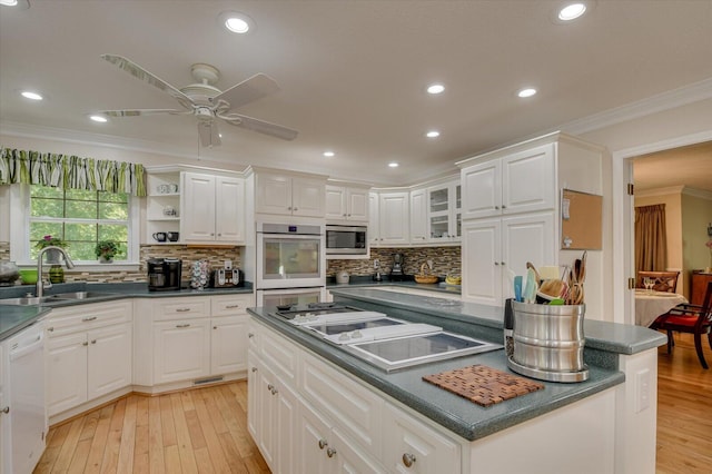 kitchen with white cabinetry, stainless steel microwave, sink, crown molding, and white dishwasher