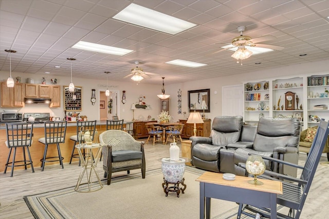 living room featuring a paneled ceiling, ceiling fan, and light wood-type flooring