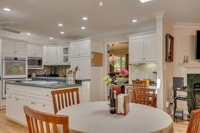 kitchen with light wood-type flooring, white cabinetry, stainless steel microwave, and crown molding