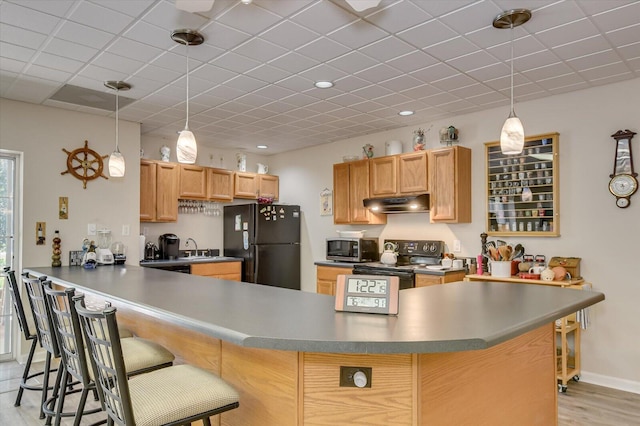 kitchen featuring pendant lighting, a kitchen breakfast bar, black refrigerator, light hardwood / wood-style flooring, and kitchen peninsula