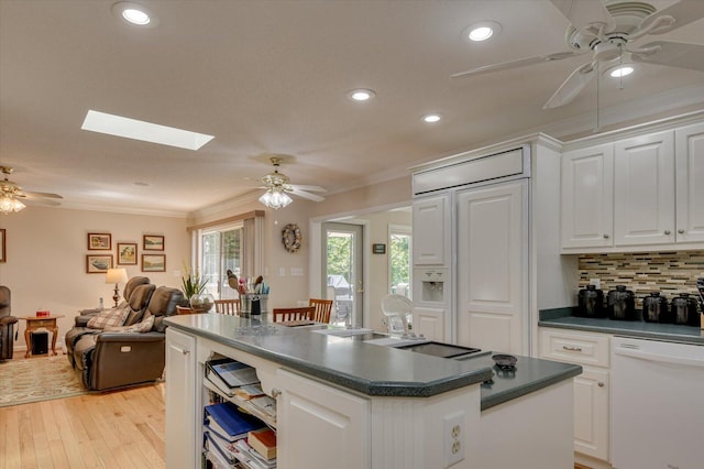 kitchen featuring white cabinets, dishwasher, decorative backsplash, and a skylight