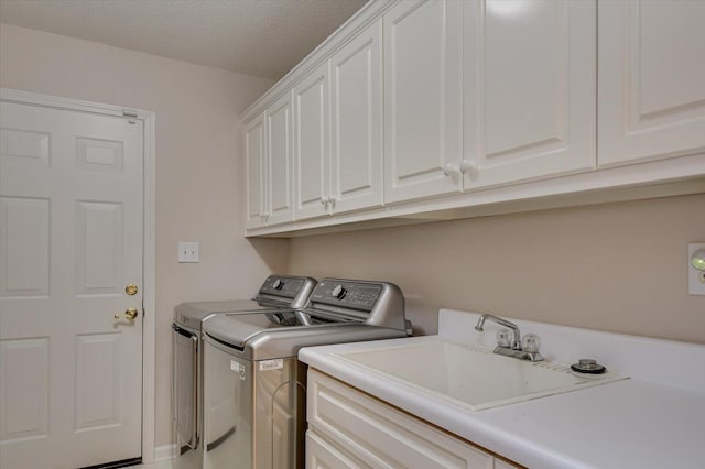 laundry room featuring cabinets, a textured ceiling, washer and clothes dryer, and sink