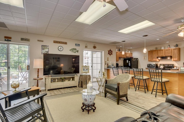 living room featuring ceiling fan and a drop ceiling