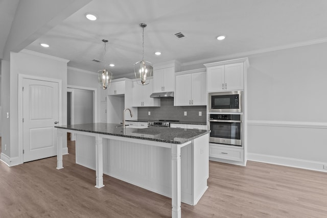 kitchen with sink, dark stone countertops, an island with sink, appliances with stainless steel finishes, and white cabinetry