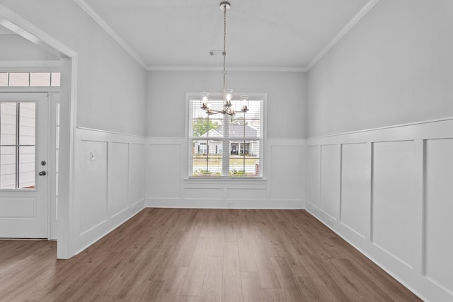 unfurnished dining area featuring a chandelier, wood-type flooring, and ornamental molding