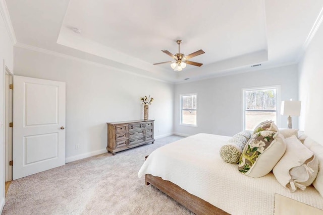 carpeted bedroom with ceiling fan, ornamental molding, and a tray ceiling