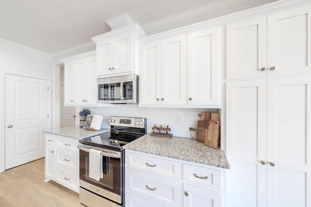 kitchen with crown molding, appliances with stainless steel finishes, white cabinetry, light stone counters, and tasteful backsplash