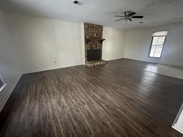 unfurnished living room featuring a textured ceiling, ceiling fan, dark hardwood / wood-style flooring, and a fireplace