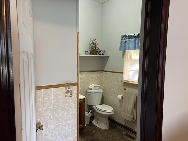 bathroom featuring toilet, tile walls, and vanity