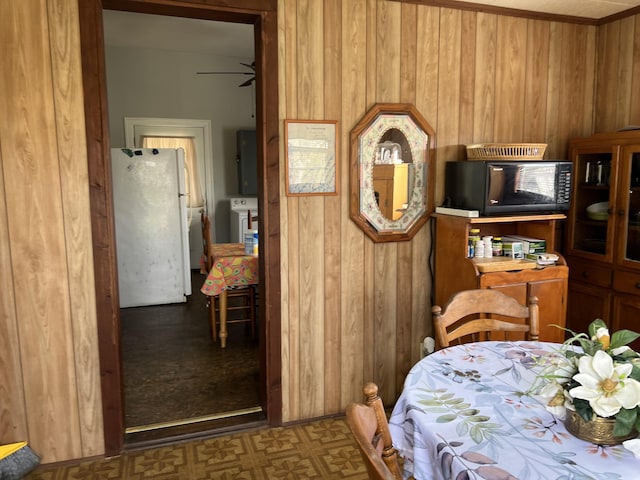 dining room featuring ceiling fan, washer / dryer, and wooden walls