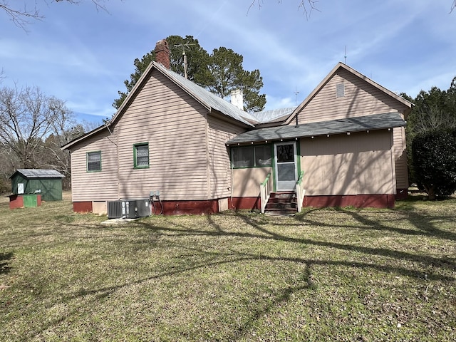 back of house featuring central air condition unit and a lawn