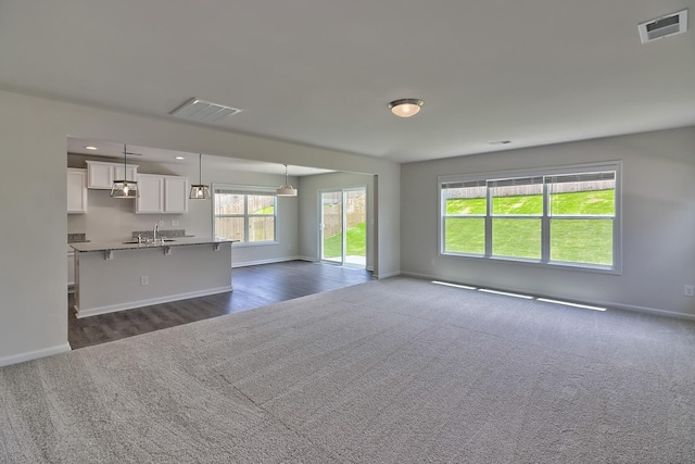 unfurnished living room with dark colored carpet and sink