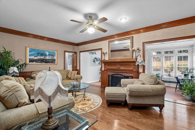 living room with a brick fireplace, crown molding, ceiling fan, and hardwood / wood-style flooring