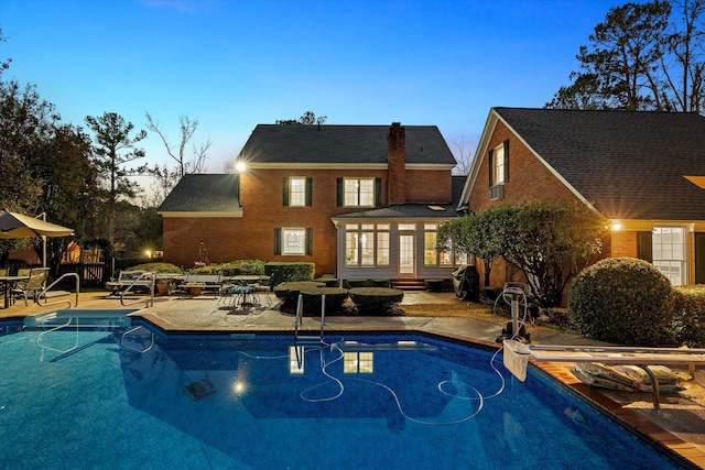 pool at dusk featuring a patio area