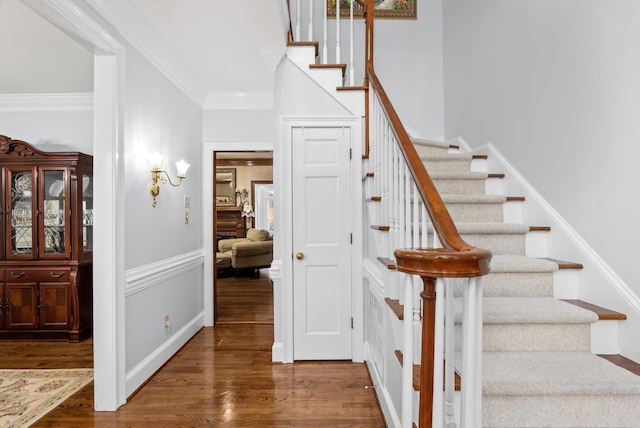 stairs with ornamental molding and hardwood / wood-style floors