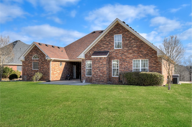 view of front of home featuring central air condition unit, a patio area, a front lawn, and brick siding