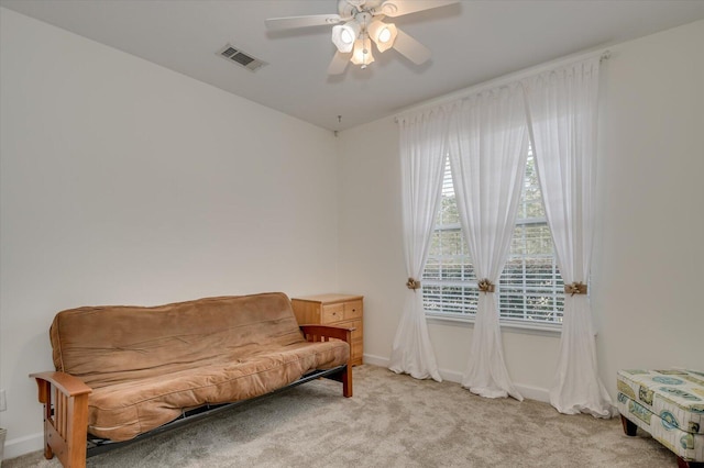 sitting room with a ceiling fan, light carpet, visible vents, and baseboards