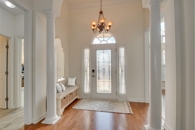 foyer entrance with a wealth of natural light, decorative columns, and light wood finished floors