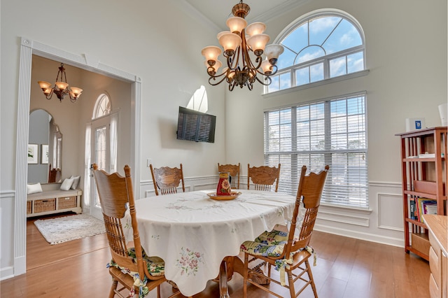 dining room featuring a wainscoted wall, a decorative wall, a notable chandelier, and wood finished floors