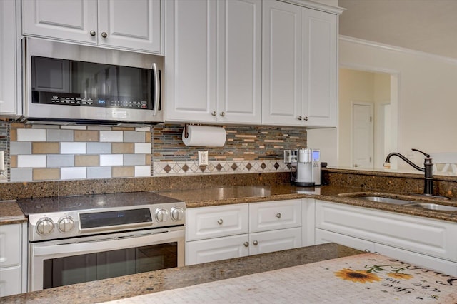 kitchen with dark stone counters, stainless steel appliances, a sink, and white cabinetry