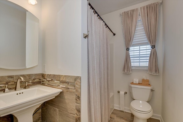 full bathroom featuring baseboards, a sink, toilet, and shower / bath combo with shower curtain