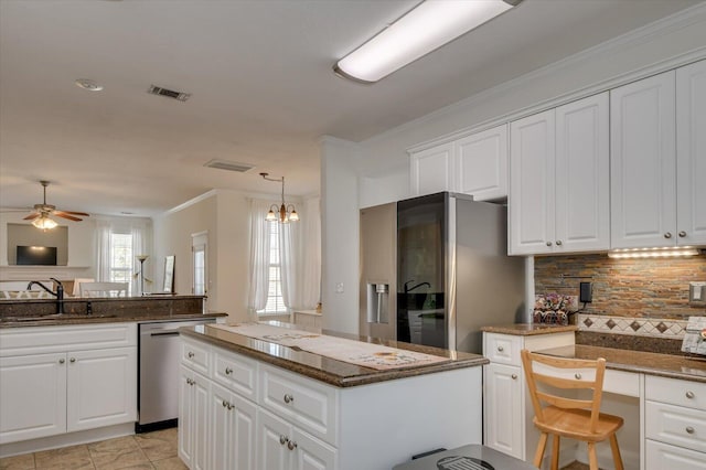 kitchen with visible vents, a kitchen island, appliances with stainless steel finishes, white cabinetry, and a sink