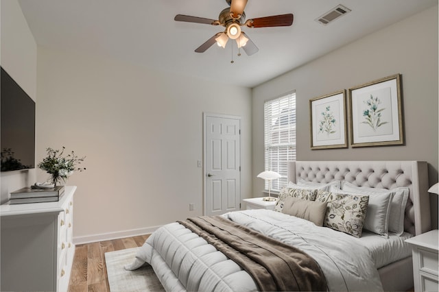 bedroom featuring light wood-type flooring, visible vents, ceiling fan, and baseboards