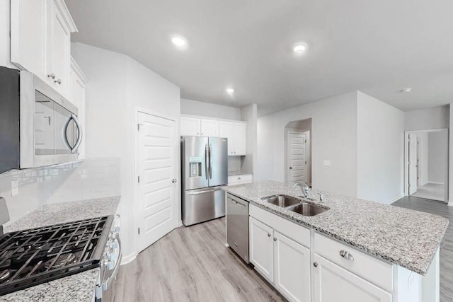 kitchen with appliances with stainless steel finishes, an island with sink, white cabinetry, and sink