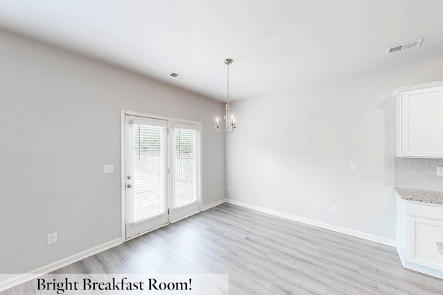 unfurnished dining area featuring an inviting chandelier and light wood-type flooring