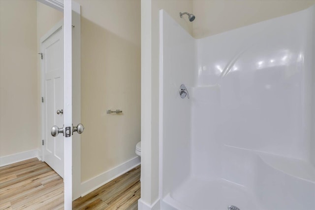 bathroom featuring hardwood / wood-style floors, toilet, and a shower