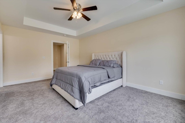 bedroom featuring a raised ceiling, ceiling fan, and light colored carpet