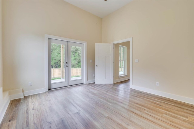 empty room featuring a towering ceiling and light hardwood / wood-style flooring