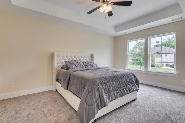 carpeted bedroom featuring a raised ceiling and ceiling fan