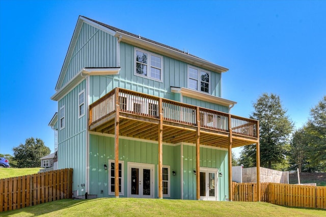 rear view of house with a yard, a wooden deck, and french doors