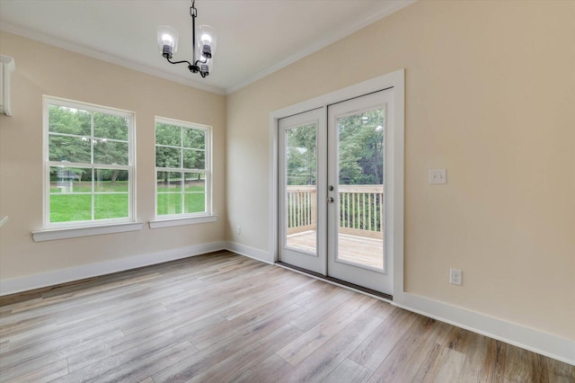 entryway featuring crown molding, french doors, a chandelier, and light wood-type flooring