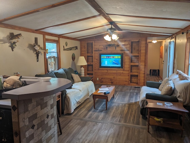 living room with wooden walls, dark wood-type flooring, ceiling fan, and lofted ceiling with beams